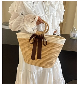 Detailed close-up of woven tote bag with a dark brown ribbon bow and hand-woven handles