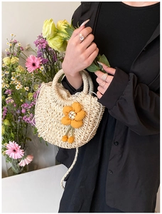 Detailed straw woven texture and yellow cloth sunflower on an ivory hand-woven summer bag