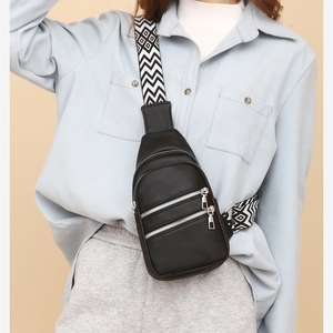 Fashionable black pebbled leather crossbody bag with three silver zippers and geometric strap