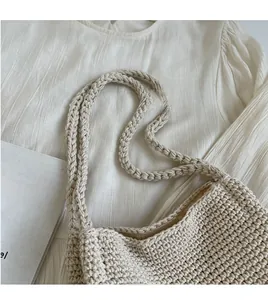Gros plan du sac à main en crochet blanc crème montrant la texture en coton et la bandoulière