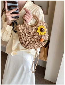Dettaglio della borsa in paglia intrecciata con girasole 3D e morbidi pompon decorativi