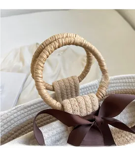 Detail of woven handbag with round handle and dark brown ribbon bow decoration