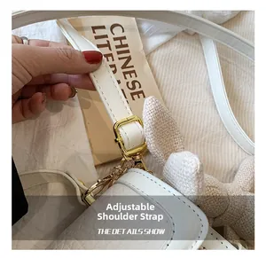 Détail de la bandoulière réglable avec boucle dorée et texture litchi sur sac en PU blanc