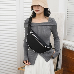 Close-up of black crossbody bag on model with white trim and silver zipper details