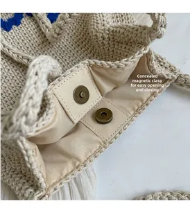 Gros plan détaillé du fermoir magnétique en bronze de ce sac à main tissé beige