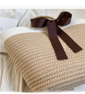 Close-up of beige woven texture and brown satin bow on minimalist handbag
