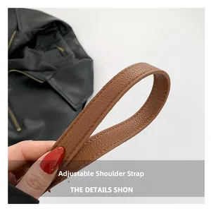 Detail showing the adjustable brown pebble leather strap with fine stitching on a bag