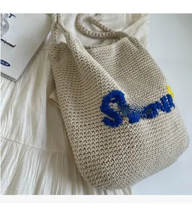 Gros plan du sac bandoulière beige tissé main avec broderie Summer sur le tissu