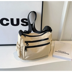 Minimalist beige canvas shoulder bag with dual black zipper pockets and wide nylon strap