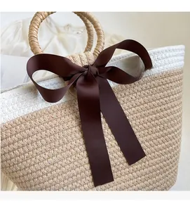 Close-up of woven straw handbag with brown bow and circular handles for summer