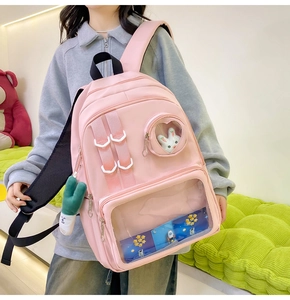 Detailed view of pink nylon backpack featuring a large transparent window and plush pendant
