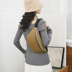 Rear view of khaki cross-body chest bag worn over a grey sweater in a minimalist room