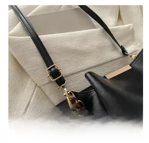 Détail de la bandoulière noire mate réglable avec boucle dorée et chaîne pour sac à main
