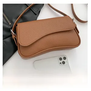 Macro shot of brown pebble grain faux leather handbag with unique curved flap design