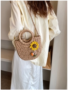 Dettaglio borsa in paglia intrecciata con girasole giallo e chiusura a coulisse