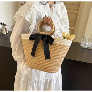 Close-up of woven tote bag with a black silk bow and textured dual-tone finish