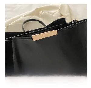 Détail d'un sac seau noir texturé avec bandoulière en chaîne dorée et fermoir métallique