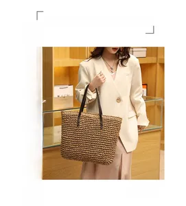Close-up of a large capacity woven straw tote bag with brown leather shoulder straps
