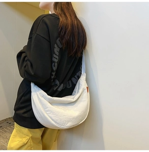 Detailed view of a white nylon crescent crossbody bag worn with casual streetwear style