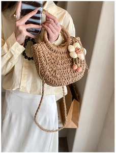 Detail of woven straw shoulder bag with floral charm and drawstring closure