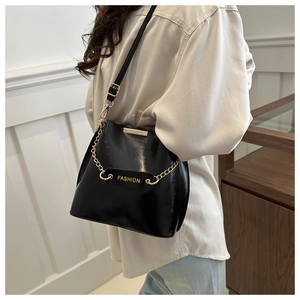 Détail du sac bandoulière en cuir verni noir avec chaîne dorée et bordure en métal