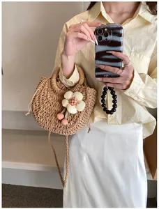 Detailed close-up of straw woven bag with 3D floral accent and secure drawstring closure
