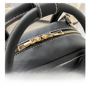 Detail of premium black pebble leather handbag with gold zippers and white stitching