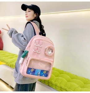 Detail view of pink nylon backpack featuring a transparent window and cute plush accessories