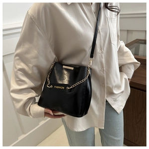 Détail du sac seau noir brillant avec chaîne dorée et étiquette cuir FASHION