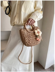 Detail shot of handwoven straw bag with natural raffia texture and white fabric flower charm