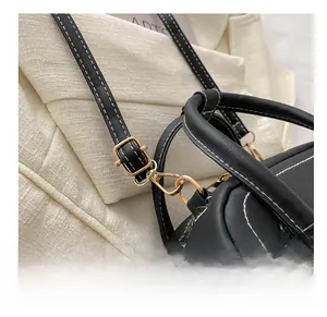 Close-up of golden hardware hook and contrast stitching on black leather handbag