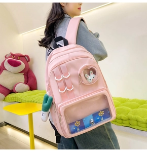 Detail view of pink nylon ita bag with heart-shaped transparent window and cute pendant