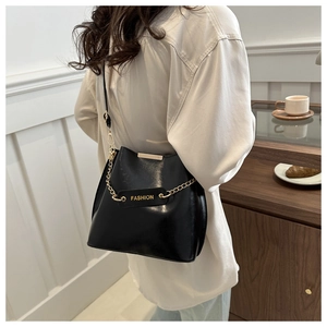 Détail d'un sac seau chic en cuir noir avec chaîne dorée et étiquette de mode