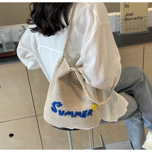 Gros plan détaillé d'un sac cabas tissé beige avec broderie Summer bleue et fleurs