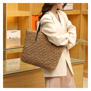 Detail of woven straw tote bag with brown leather straps shown in a luxury boutique