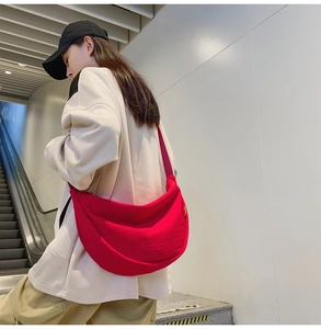 Detail of red nylon crescent crossbody bag with adjustable strap on female model