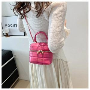 Gros plan du sac bandoulière rose matelassé avec chaîne dorée porté par un mannequin