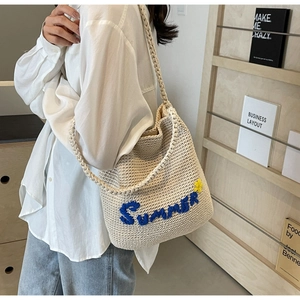 Détail du sac seau tissé beige avec broderie Summer et petite fleur décorative