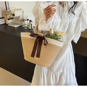 Detailed texture of woven straw tote bag with silk bow and round handle on café background
