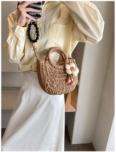Detailed view of handmade straw crossbody bag with floral charms and beaded handle