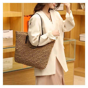 Detail of the high-quality woven straw texture and leather handle on the tote bag