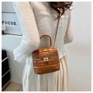 Détail d'un sac à main cube marron matelassé avec fermetures éclair à boules dorées