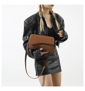 Detailed macro view of brown pebbled leather texture on a modern crossbody bag