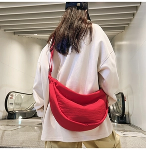 Detail of large red nylon crescent crossbody bag with adjustable strap and zipper closure