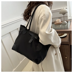 Détail du sac cabas minimaliste en nylon noir porté par un mannequin dans un cadre chic