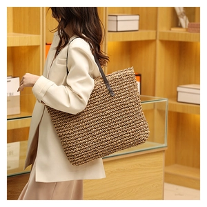 Detailed side view of woven straw tote bag with premium leather handles on model