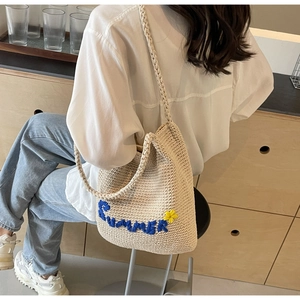 Détail du sac d'été tricoté beige avec texte SUMMER bleu et petite fleur jaune décorative