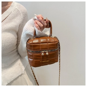 Détail d'un sac à main carré marron matelassé avec bandoulière et zip à boule dorée