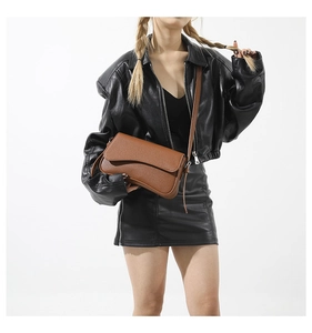 Close-up of brown litchi pattern leather handbag on a model with black jacket