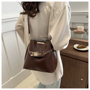 Détail du sac seau en cuir PU marron foncé avec chaîne en métal et étiquette de mode